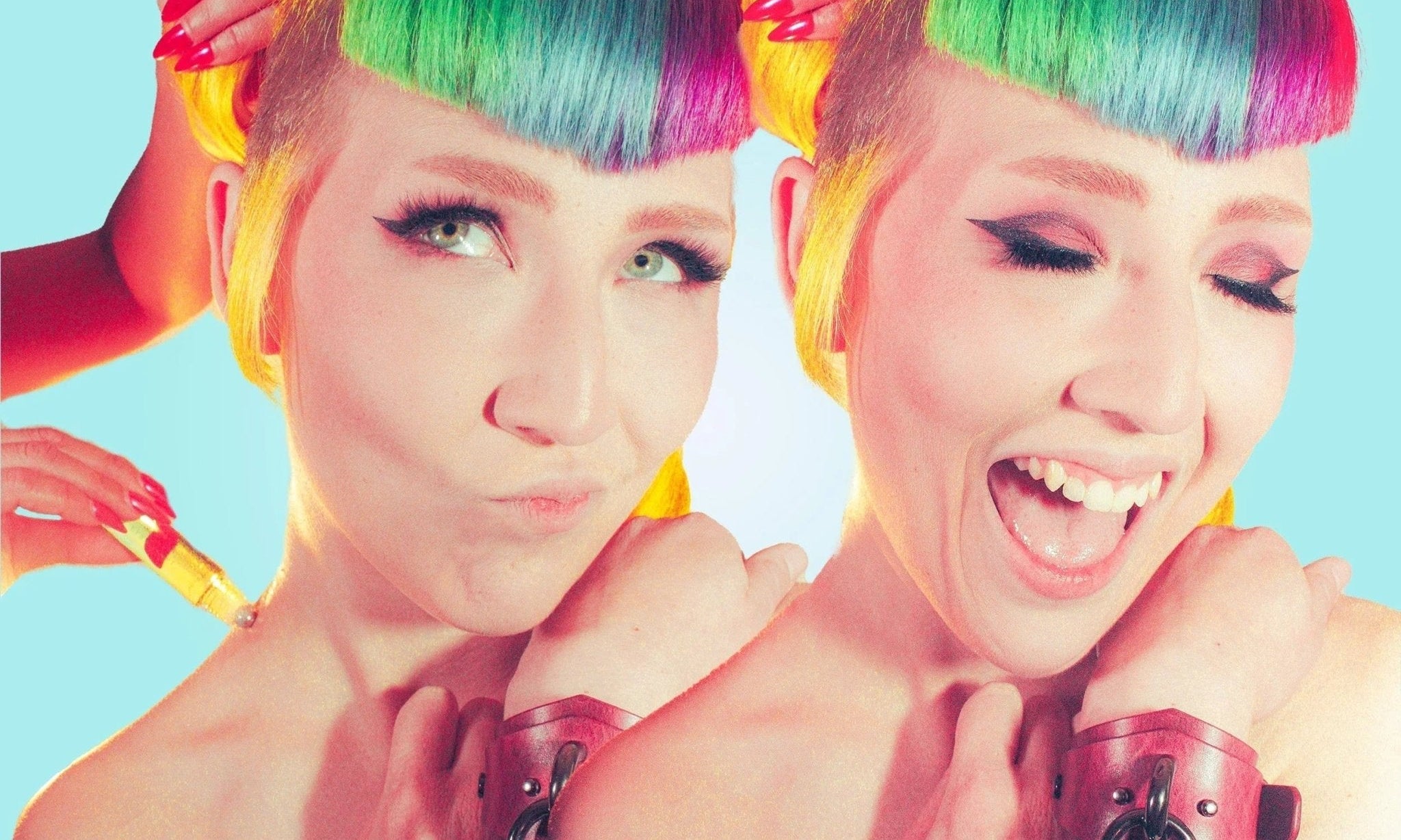 Person with vibrant rainbow hair wearing leather wrist cuffs with metal rings, close-up portrait with bright blue background