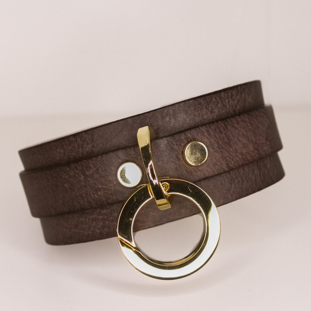 Luxurious 'Mesa' brown leather BDSM collar featuring a polished gold-tone O-ring and button studs against a white backdrop for a high-contrast presentation.