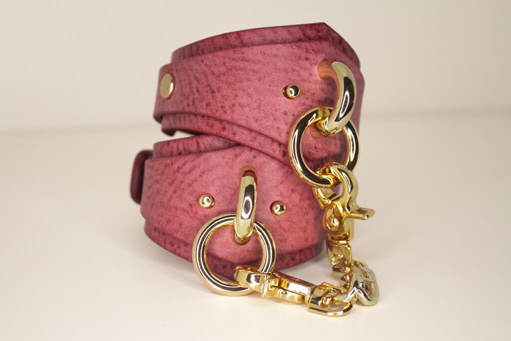 Artisanal Desert Rose Italian leather BDSM cuffs with gold-tone hardware, displayed against a neutral backdrop.