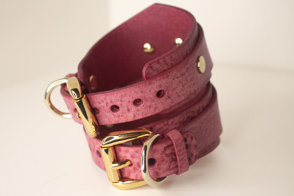 Hand wearing a Desert Rose Italian leather BDSM cuff, connected by a luxurious gold-tone chain.