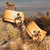 Natural leather day collar and wrist cuffs with gold hardware on desert cactus background