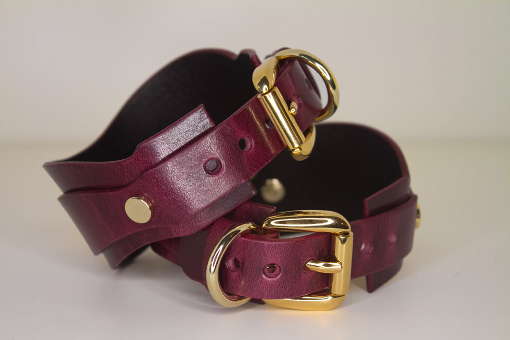 Back detail of Bordeaux leather BDSM cuffs with gold-tone buckle and loop.