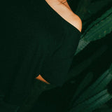 Person wearing a gray custom leather day collar with a metal ring, black off-shoulder top, dark background