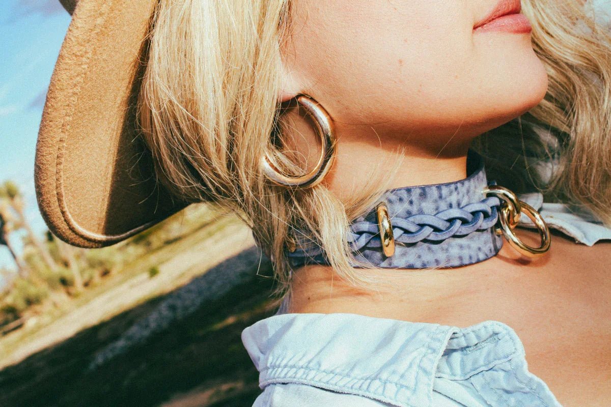 side view woman outside wearing cowboy core blue leather bdsm collar and hat