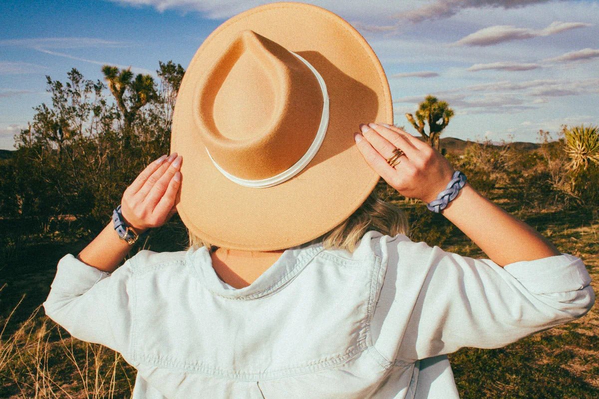 woman facing away wearing blue leather cowboy core festival fashion and hat
