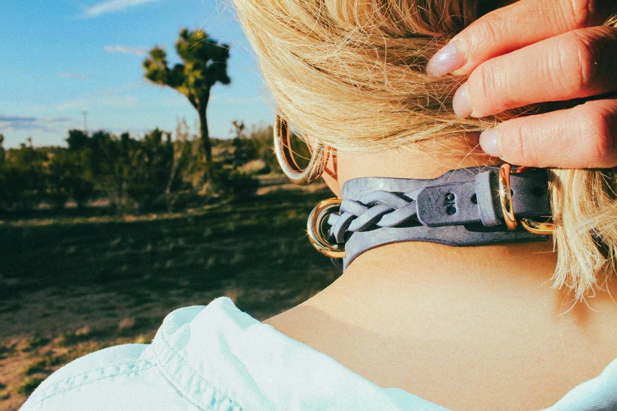 rear view view woman outside wearing cowboy core blue leather bdsm collar
