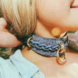 Woman wearing a blue leather day collar with gold rings and matching leather wrist cuffs outdoors