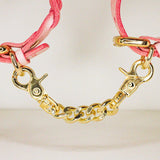 Pink leather wrist cuffs connected by gold chain with gold clasps, leather collars detail
