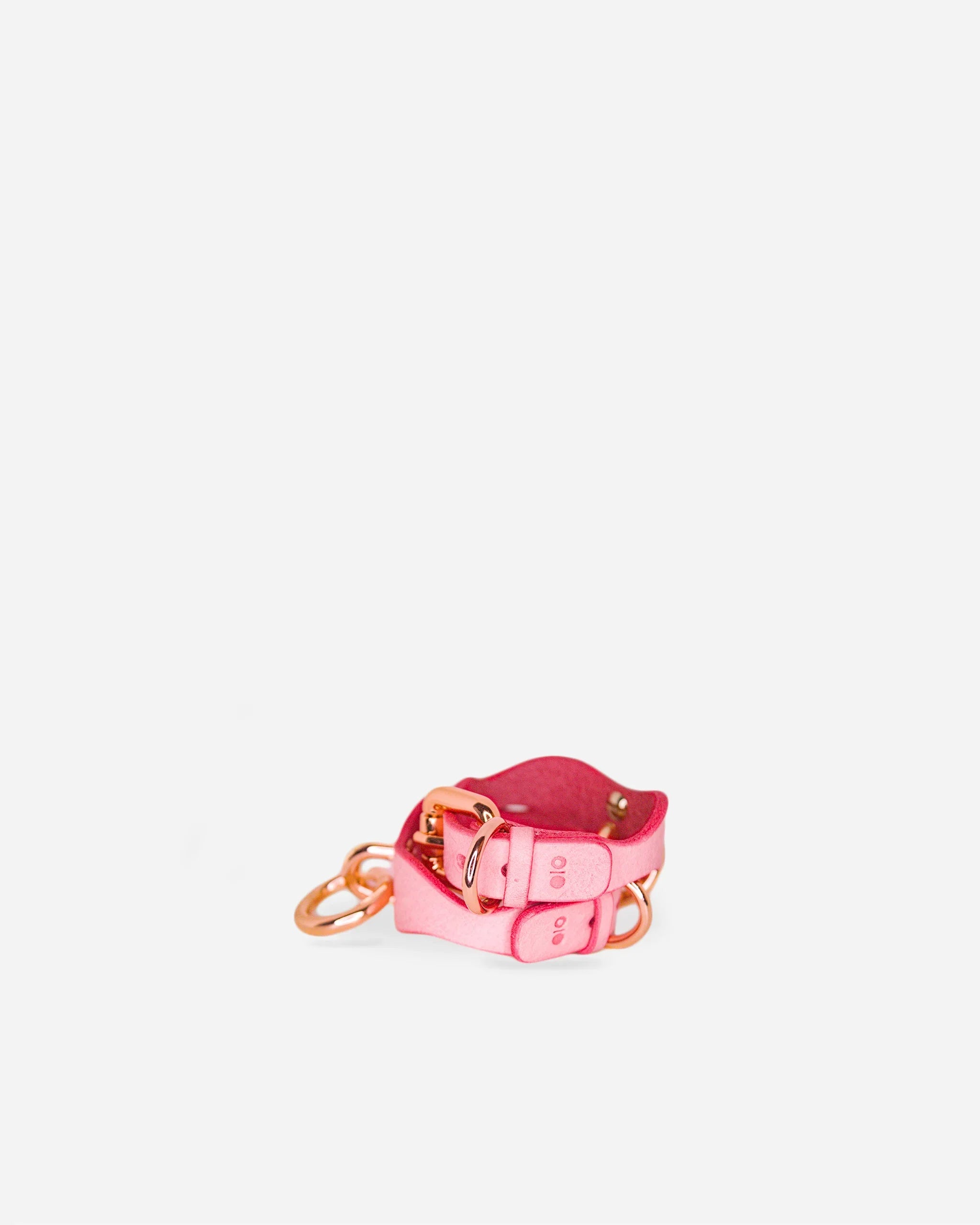 Pink leather day collar with rose gold hardware and matching leather wrist cuffs on white background