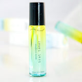 Neon Coyotes brat tamer pocket perfume bottle with black cap on reflective surface, background blurred