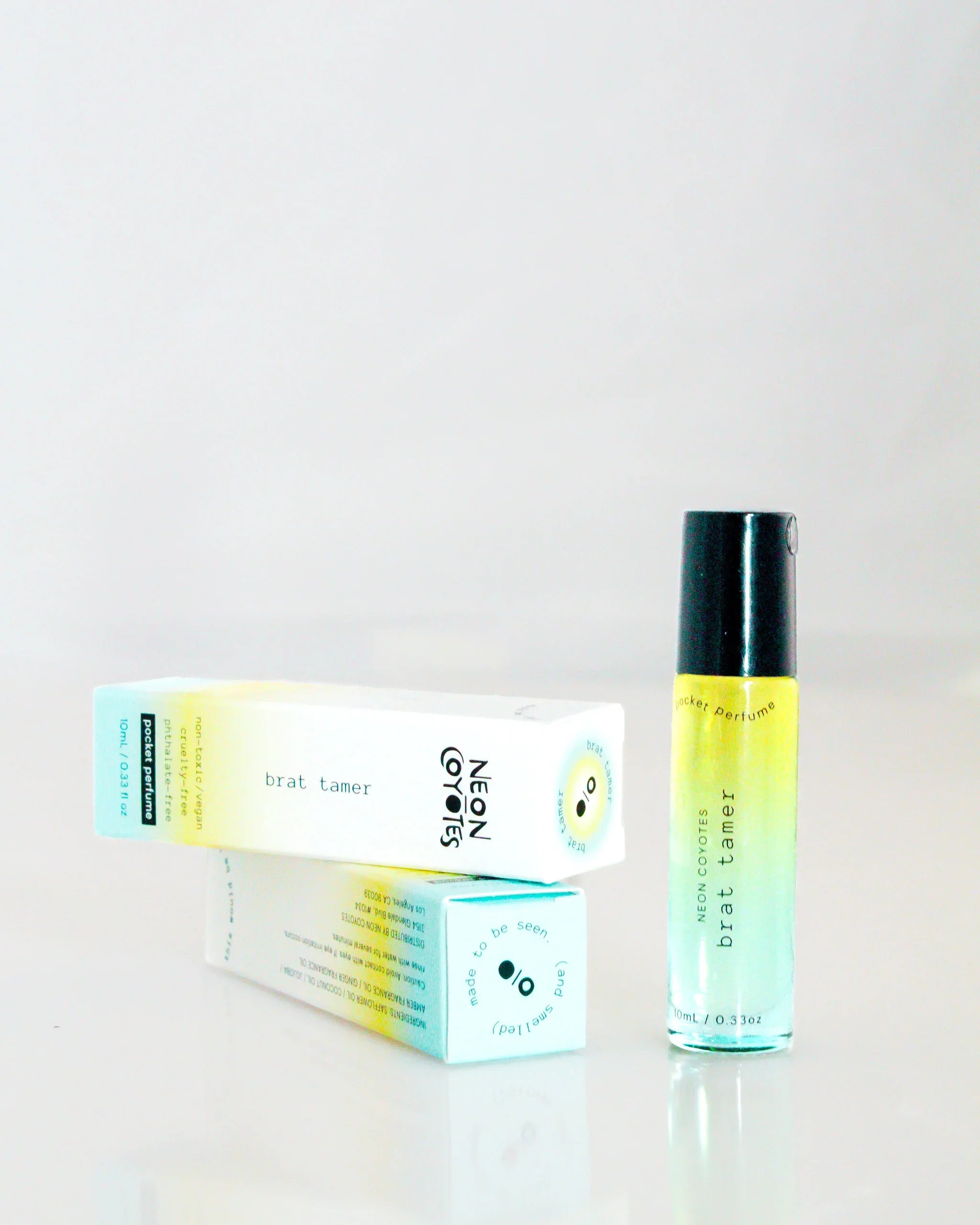 Neon Coyotes Brat Tamer pocket perfume bottle with branded packaging on a white surface