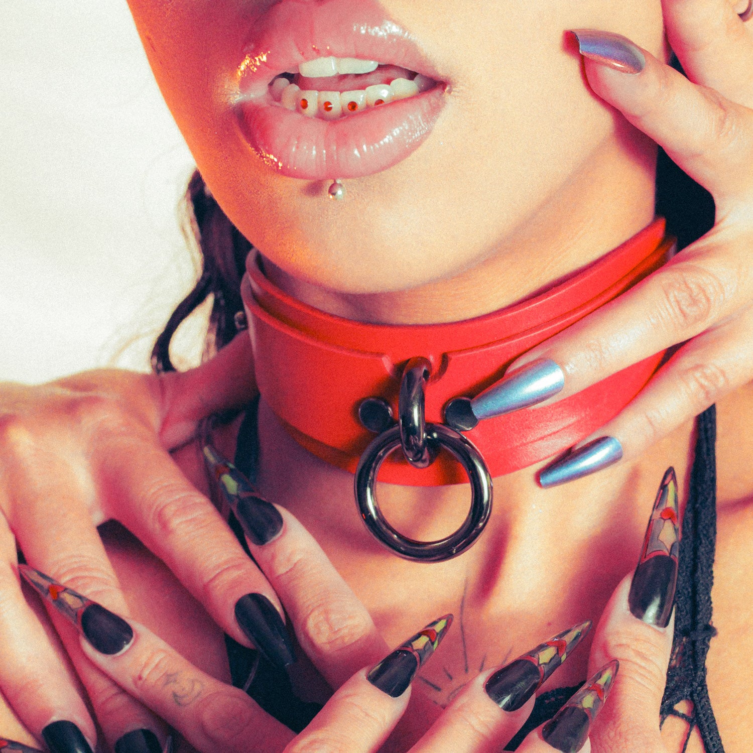 Close-up of a person wearing a red leather choker with a metal ring detail.