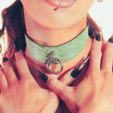 Close-up of a person wearing a green day collar with a silver ring detail.