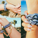 Braided and buckle leather cuffs in denim blue worn on wrists outdoors with clear sky background
