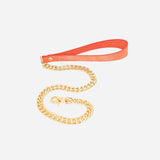 Orange leather wrist cuffs with gold chain leash on white background, featuring custom leather design.