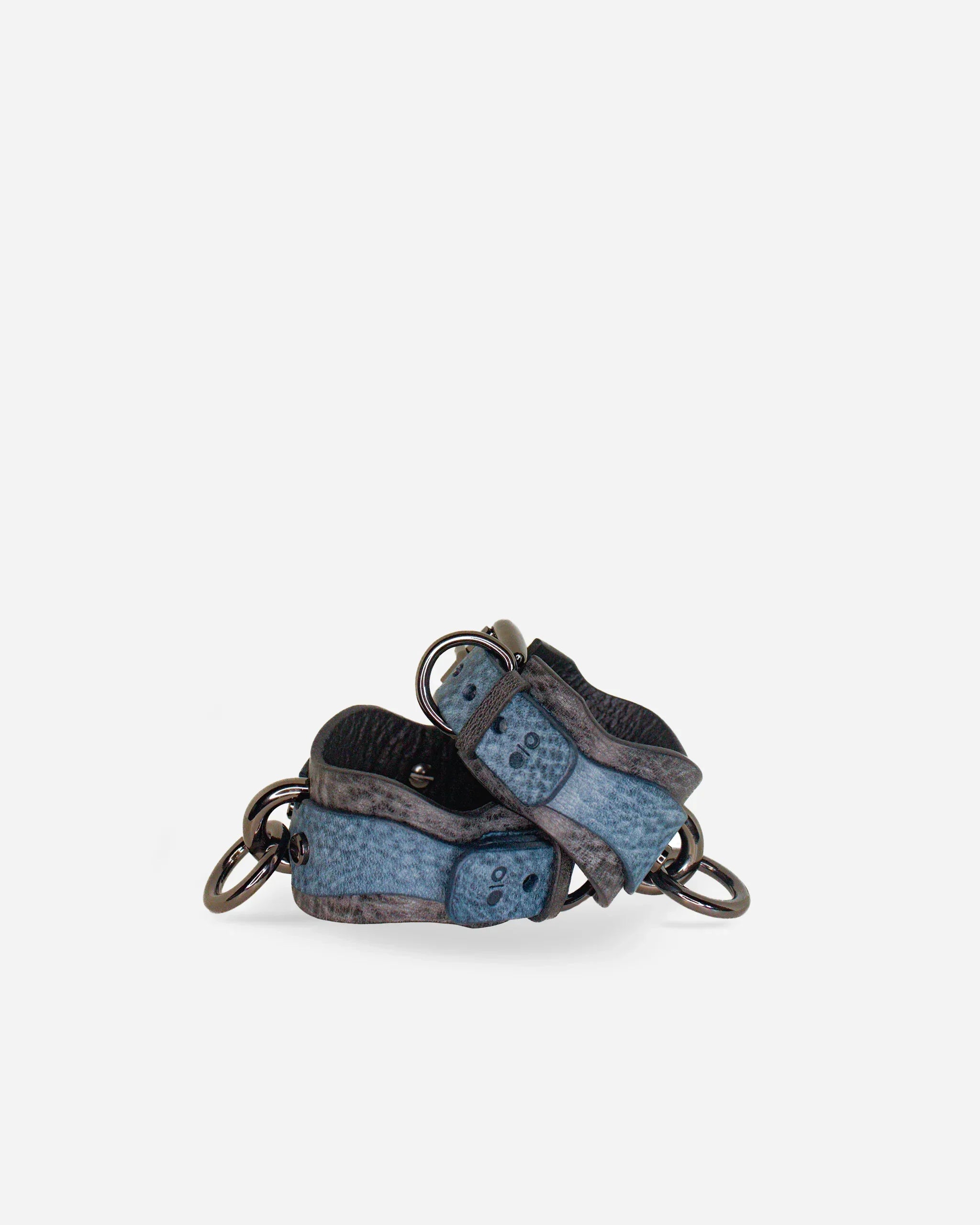 Pair of blue and gray leather wrist cuffs with metal rings on white background, handmade leather cuffs