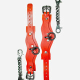 Pair of red leather wrist cuffs with silver buckles and rings, accompanied by two silver chain connectors