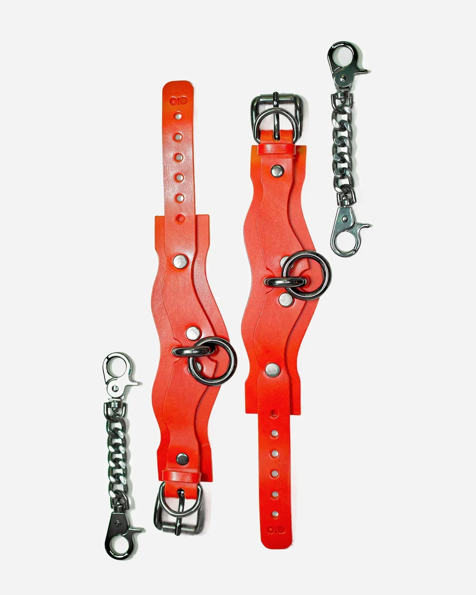 Pair of red leather wrist cuffs with silver buckles and rings, accompanied by two silver chain connectors