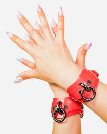 custom red leather cuffs with black rings on a white background