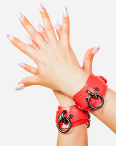 custom red leather cuffs with black rings on a white background