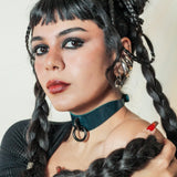 Woman with dark braided hair wearing a teal leather day collar with black ring, and black top
