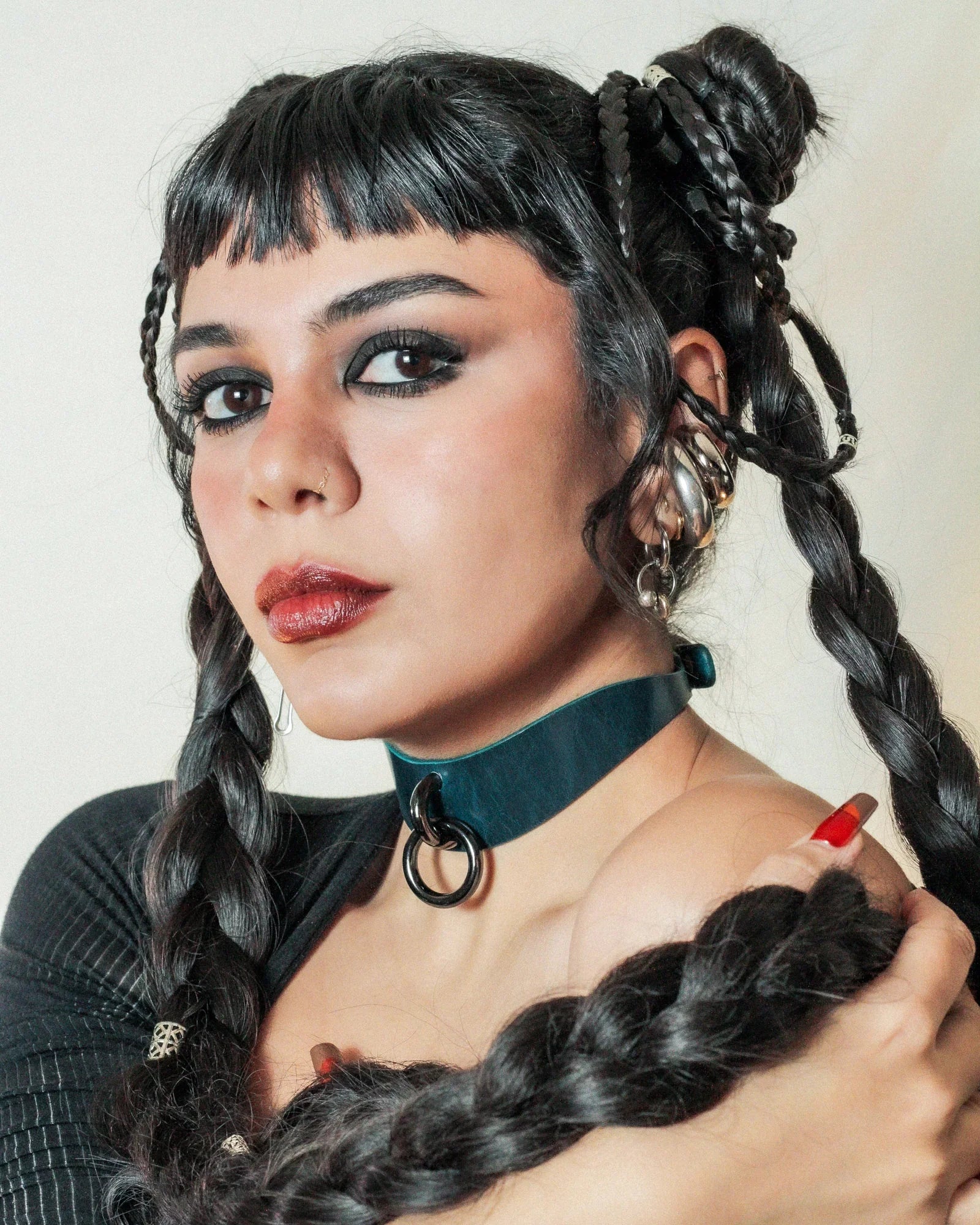 Woman with dark braided hair wearing a teal leather day collar with black ring, and black top