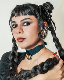 Woman with dark braided hair wearing a teal leather day collar with black ring, and black top