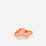 Pair of orange leather wrist cuffs with gold-tone metal rings on white background