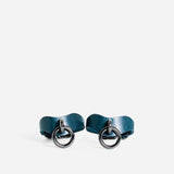 Pair of blue leather wrist cuffs with black metal rings on white background, custom leather cuffs