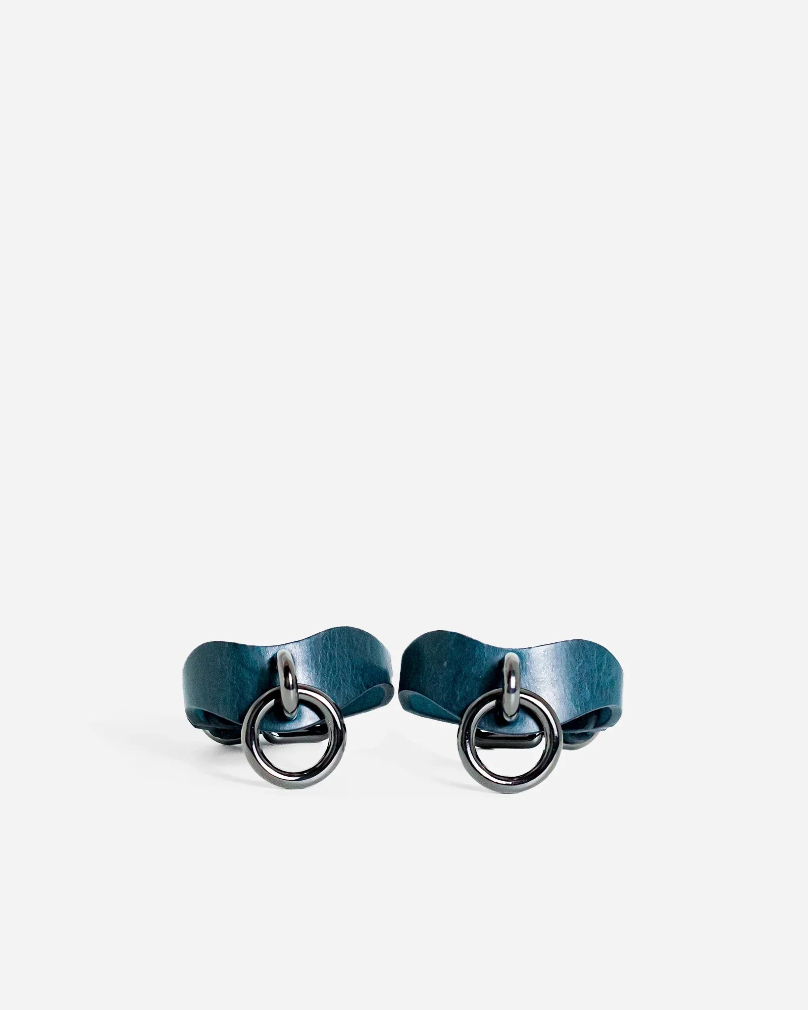 Pair of blue leather wrist cuffs with black metal rings on white background, custom leather cuffs