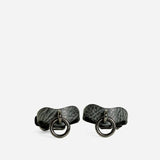 Pair of textured ash gray leather wrist cuffs with black metal O-ring hardware on white background