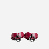 Pair of Bordeaux leather wrist cuffs with silver metal O-ring hardware on white background