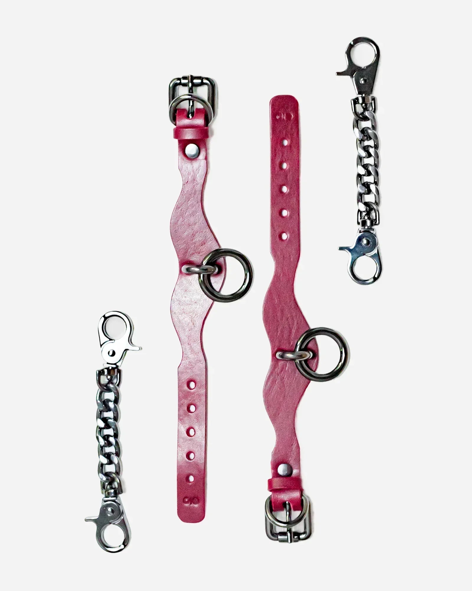 Pair of Bordeaux leather cuffs with metal rings and two detachable silver chain connectors for wrist cuffs