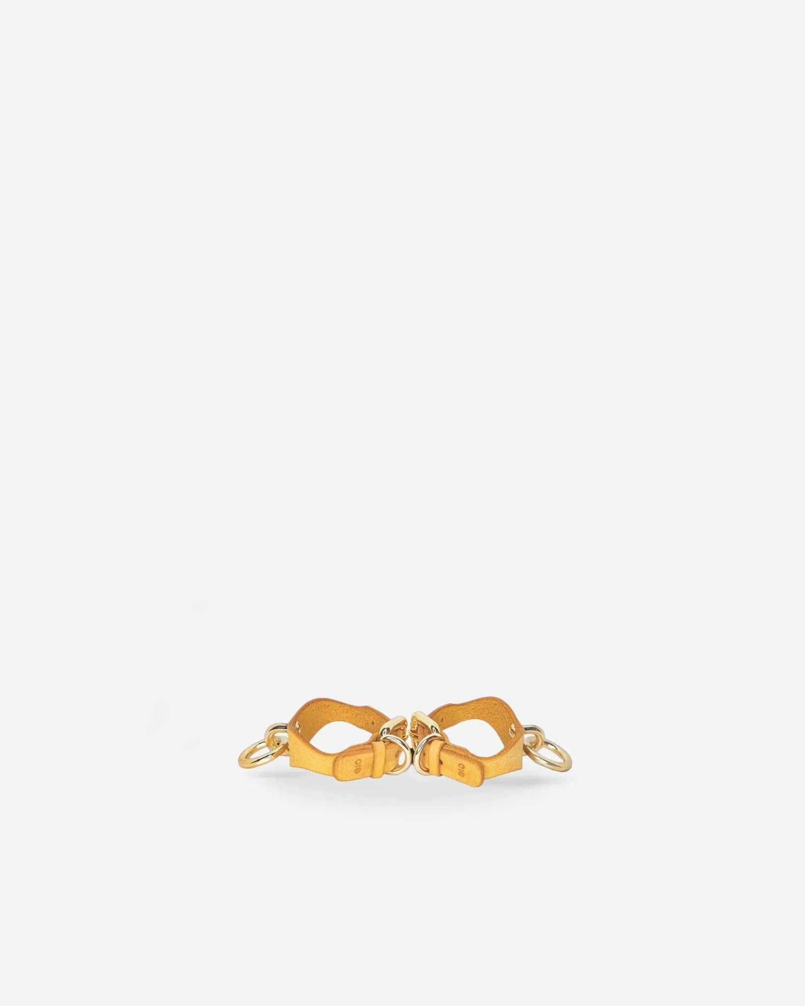 Pair of golden hour leather wrist cuffs with gold hardware on white background
