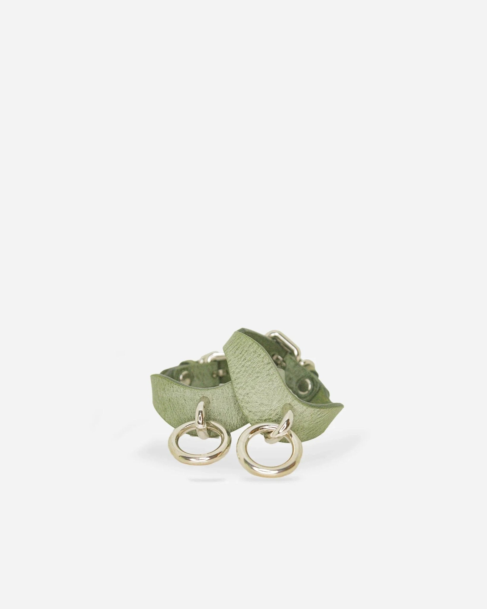 Pair of light green leather wrist cuffs with silver rings on white background