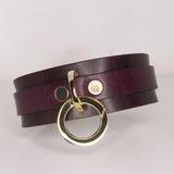The 'Milky Way' collar showcases a rich burgundy leather with a lustrous gold-tone O-ring, set against a clean, neutral backdrop to accentuate its luxe design.