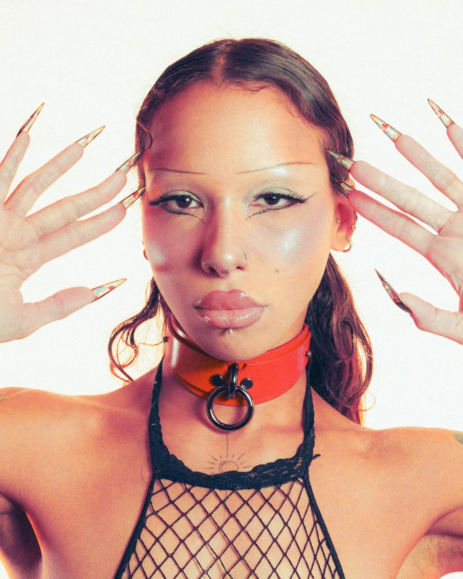 Person wearing a black fishnet top with a red leather bdsm collar against a white background
