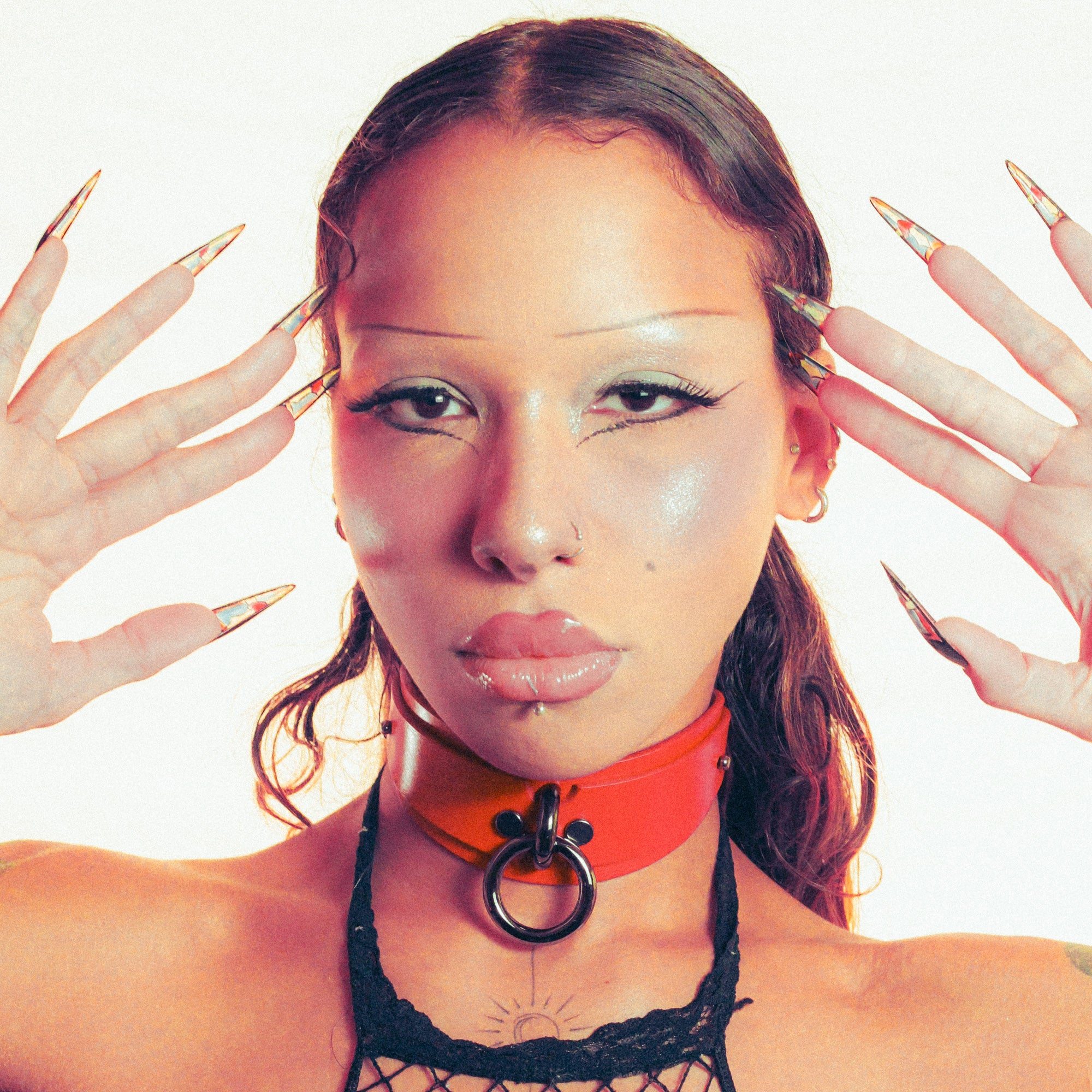 Woman with red bdsm collar and black lace top, surrounded by stylized hands with long nails.