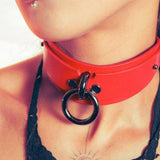 Close-up of a person wearing a red collar with a black o-ring detail.