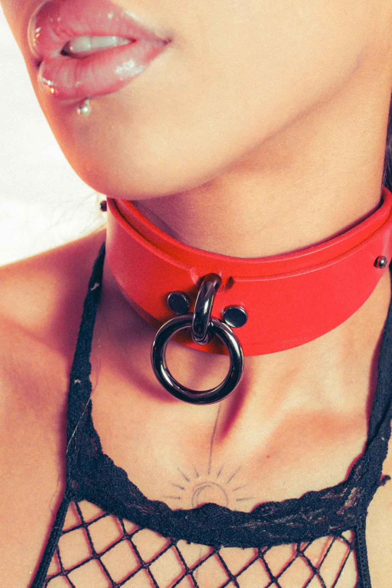 Close-up of a person wearing a red collar with a black o-ring detail.