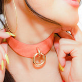 Close-up of woman wearing orange leather day collar with gold ring, showcasing custom leather collars and cuffs