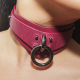 Close-up of a model wearing a magenta leather day collar with a large metallic ring detail